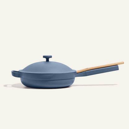 The bestselling Always Pan 2.0 is a blue nonstick frying pan with a matching lid and light wooden handle, displayed on a plain light background.