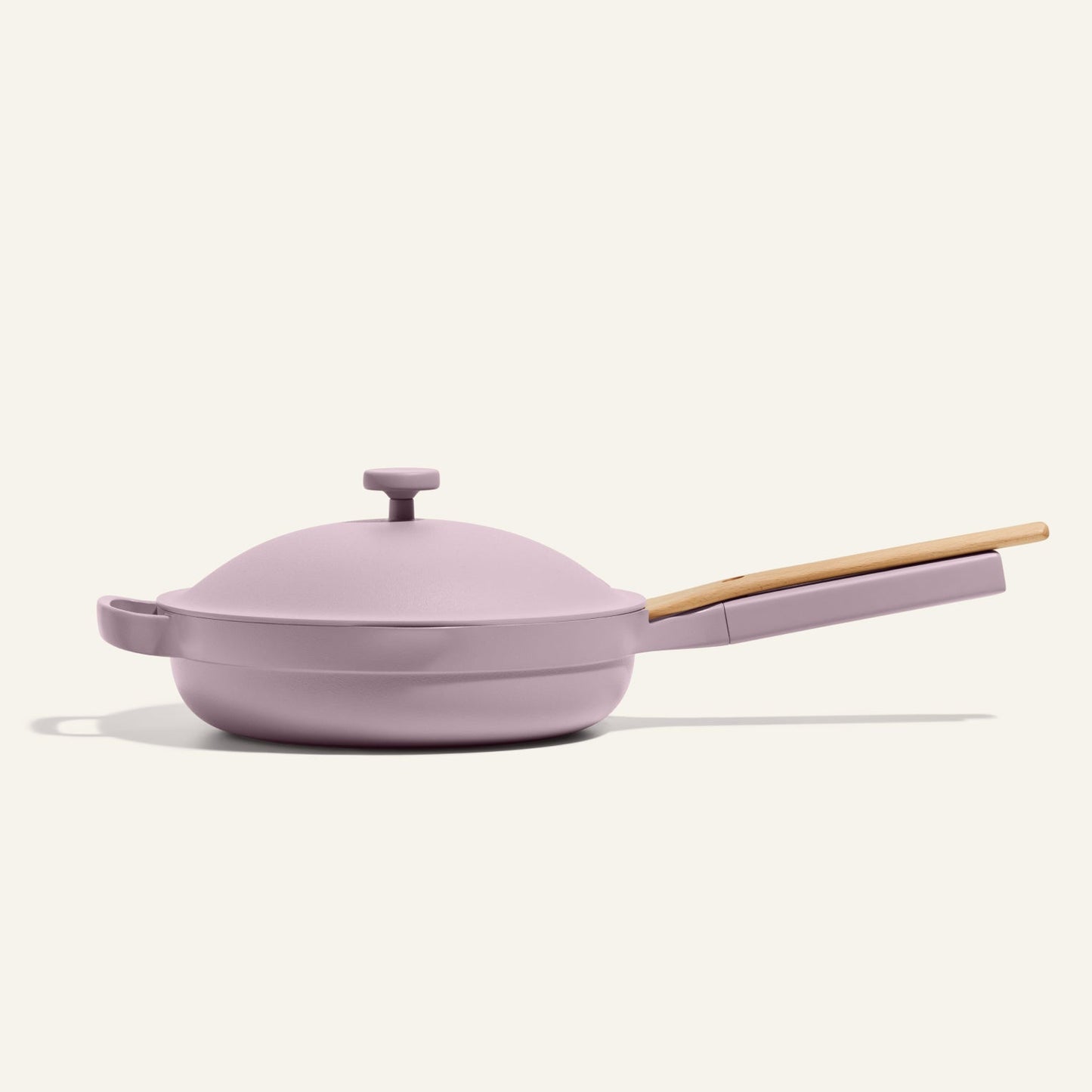 The Always Pan 2.0, a lavender nonstick pan with matching lid and light wooden handle from a bestselling cookware system, is shown against an off-white background.