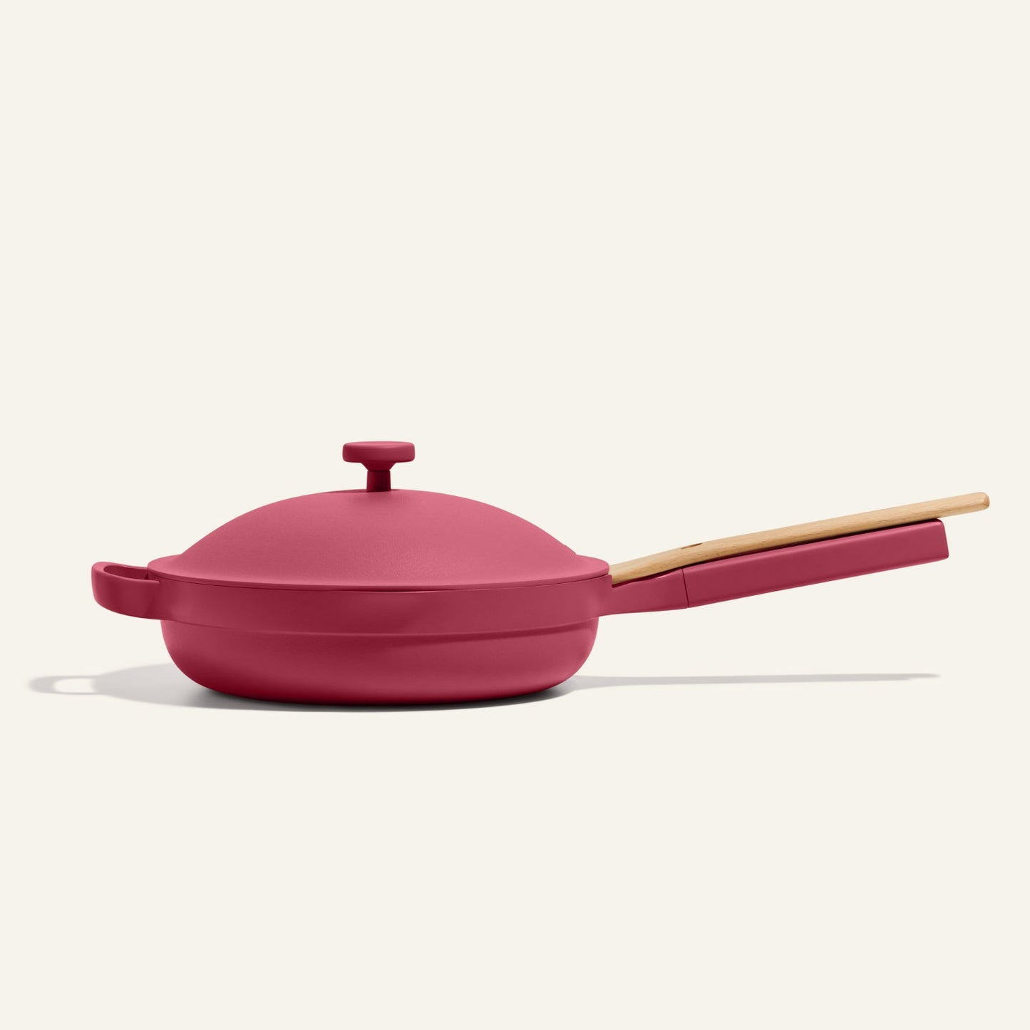 The Always Pan 2.0, a bestselling red nonstick frying pan with lid and light wooden handle, is shown on a plain light background.