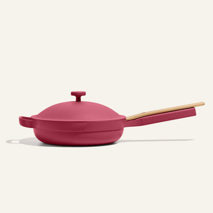The Always Pan 2.0, a bestselling red nonstick frying pan with lid and light wooden handle, is shown on a plain light background.