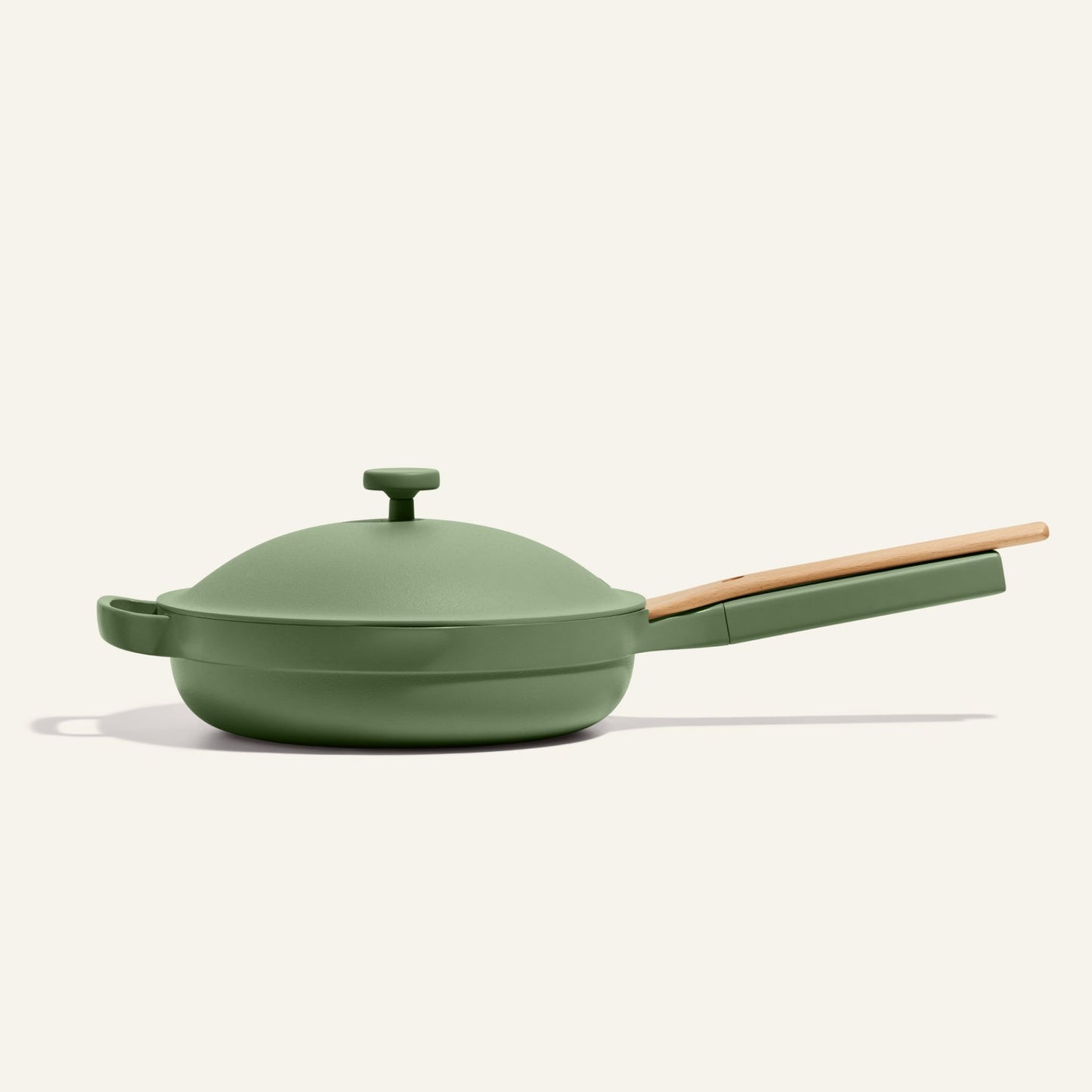 The Always Pan 2.0 is a bestselling green nonstick frying pan with a matching lid and long wooden handle, displayed on a plain light background.