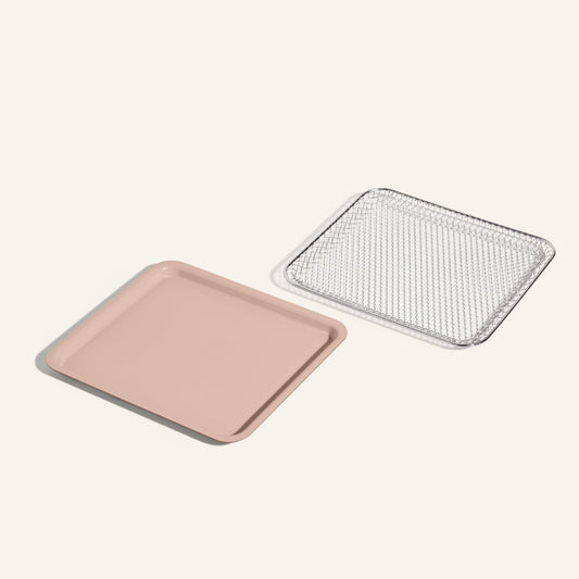 The Wonder Oven Essentials Kit features a square pink baking tray and a matching metal cooling rack side by side on a light background, providing extra components for all your baking needs.