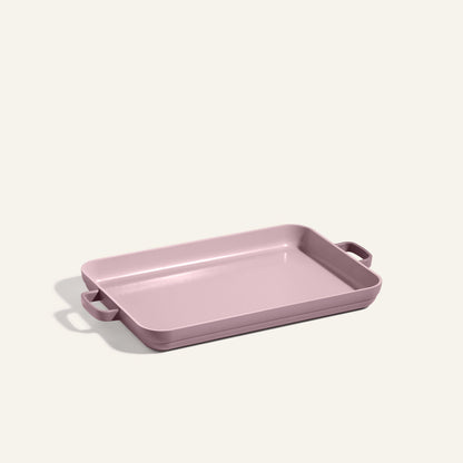A rectangular pink Griddle Pan with side handles is displayed against a plain light background, providing a stylish alternative to a nonstick sheet pan for your baking needs.