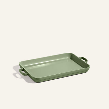 Green Griddle Pan with two side handles, set on a light surface; ideal for oven use or pairing with a nonstick sheet pan for versatile baking.