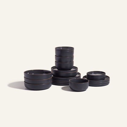 The Classic Stacking Set is a 20-piece matte black ceramic tableware collection with scratch-resistant plates, bowls, and small dishes, neatly arranged on a plain light background.