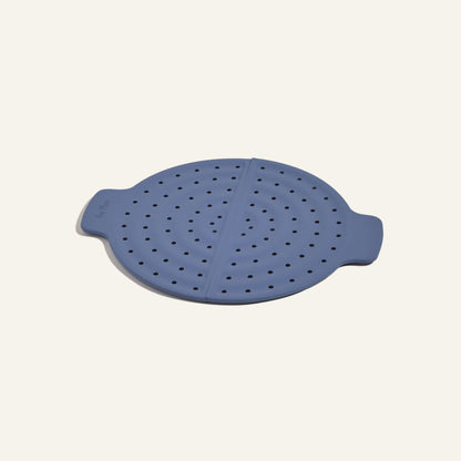The Fearless Fry is a round, blue silicone steamer insert with side handles and multiple holes for splatter prevention, designed for use with the Always Pan and shown on a plain background.
