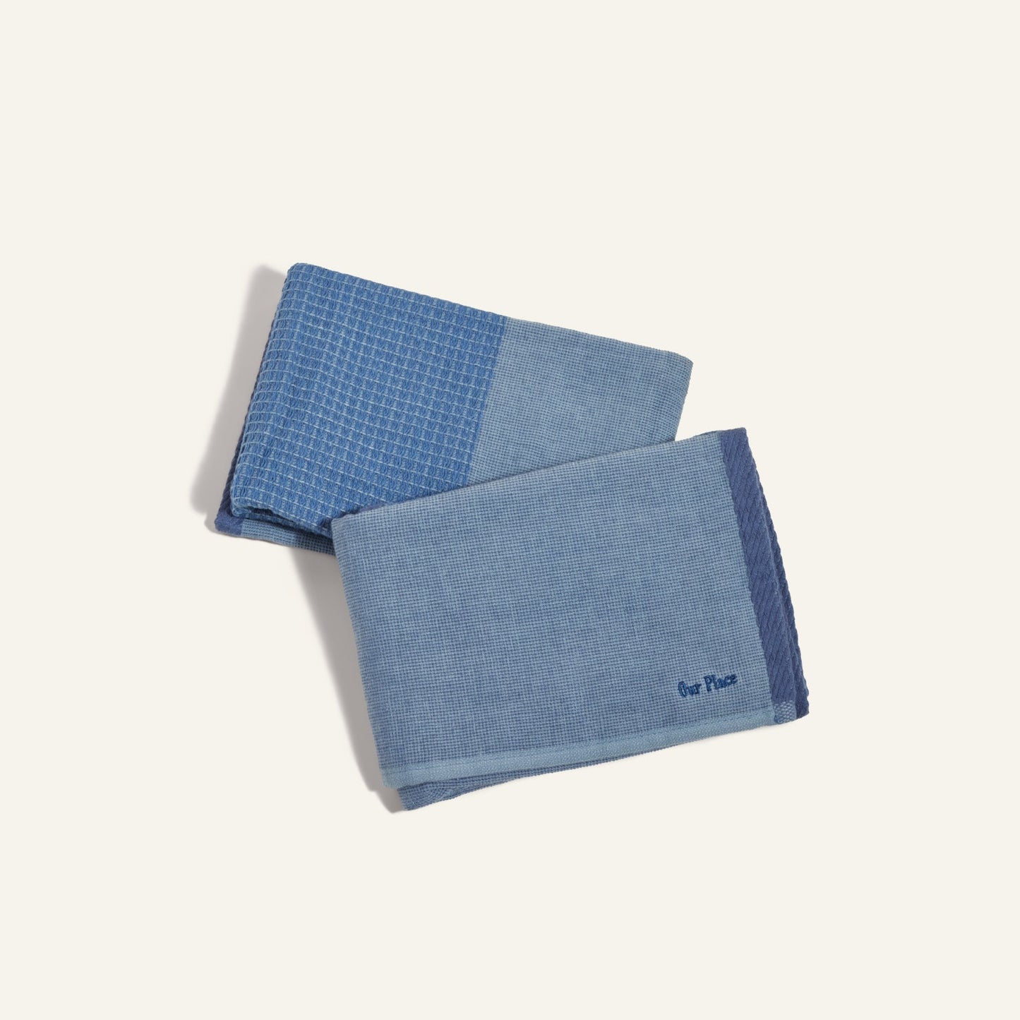 Two folded Double Dish Towels in blue, each with unique dual-textured patterns, are arranged on a light background.