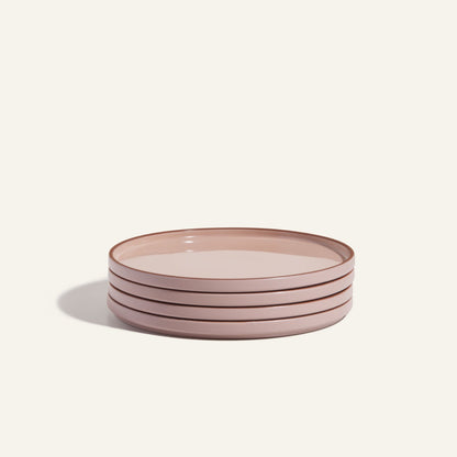 A stack of four round, light pink Dinner Plates with a hand-glazed finish and slightly raised rims is set against an off-white background—an elegant addition to any tableware collection.