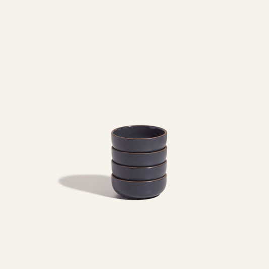 A stack of four Tiny Bowls, made from scratch resistant ceramic, is displayed on a light, neutral background.