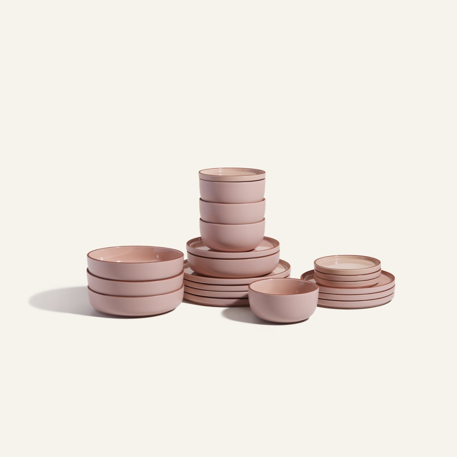 The Classic Stacking Set features pink ceramic bowls and scratch-resistant plates, neatly arranged on a light surface with a plain background.