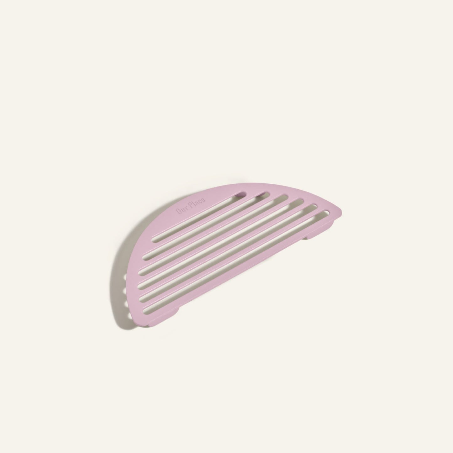 The Fry Deck, a pink semicircular slotted soap dish inspired by the sleek design of Our Place cookware and the Always Pan, is displayed on a plain off-white background.