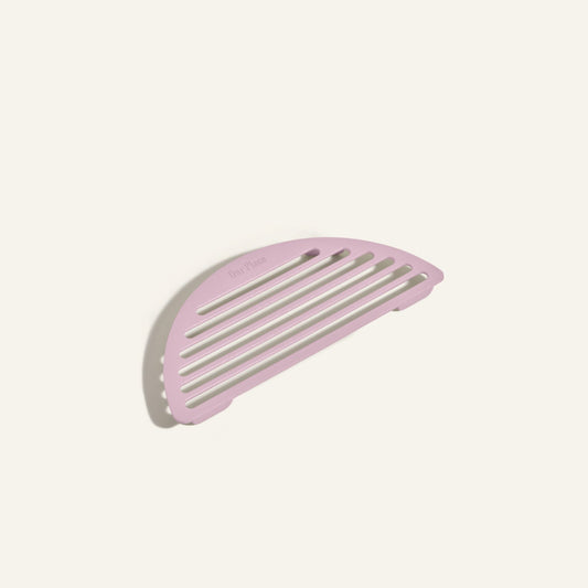 The Fry Deck, a pink semicircular slotted soap dish inspired by the sleek design of Our Place cookware and the Always Pan, is displayed on a plain off-white background.