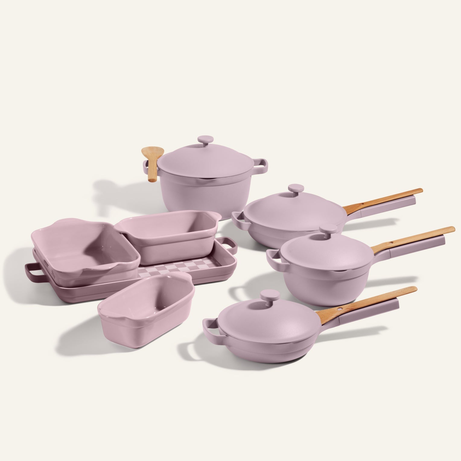 A lavender Cookware + Bakeware Set with wooden handles—including pots, pans, baking dishes, lids, and the Perfect Pot—beautifully arranged on a neutral background.