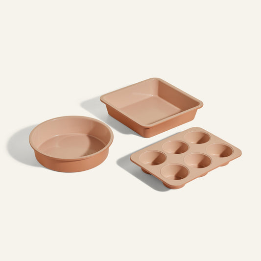 The Wonder Oven Baker’s Kit, featuring three beige nonstick, non-toxic pans—one round, one square, and a six-cup muffin pan—is arranged on a light background, ideal for your Wonder Oven.