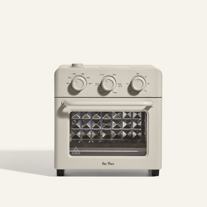 The AU - Wonder Oven is a beige toaster oven with three control dials, a glass door, and a diamond-patterned tray that doubles as an air fryer for versatile cooking.