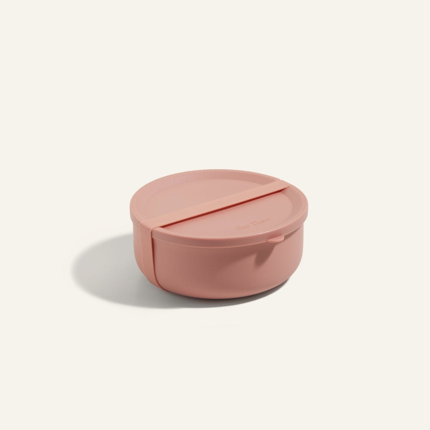 The Wander Bowl, a round pink lunch container with a matching lid, is shown on a plain background. This microwave-safe solution keeps your meals fresh and ready to enjoy.