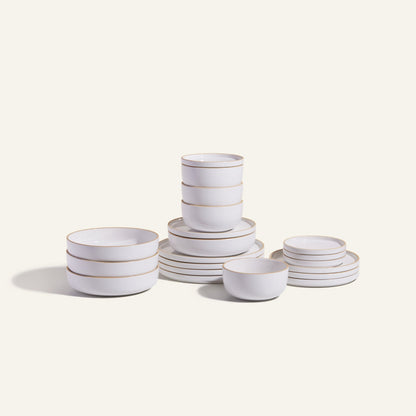 The Classic Stacking Set is a 20-piece ceramic tableware collection with matching white bowls and plates, each adorned with thin gold rims, attractively stacked against a plain light background.