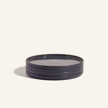 A stack of four round, dark-colored Dinner Plates with a hand-glazed finish rests on a plain light background, highlighting elegant ceramic tableware.