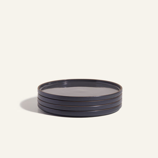 A stack of four round, dark-colored Dinner Plates with a hand-glazed finish rests on a plain light background, highlighting elegant ceramic tableware.
