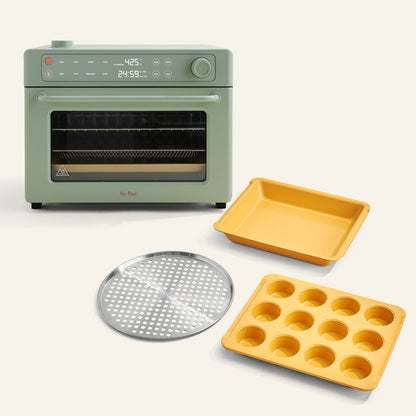 The Wonder Oven Pro + Wonder Oven Pro Chef's Kit is a green countertop convection oven with a digital display, shown with a perforated metal tray, yellow rectangular baking dish, and yellow muffin pan.