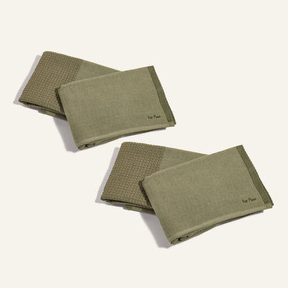 Two sets of Double Dish Towels in olive green, featuring dual textures and subtle Our Place logos, are folded and displayed on a plain light background.