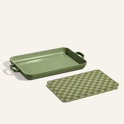 A rectangular green Griddle Pan with handles is displayed beside matching green checkered Oven Mats on a light background.