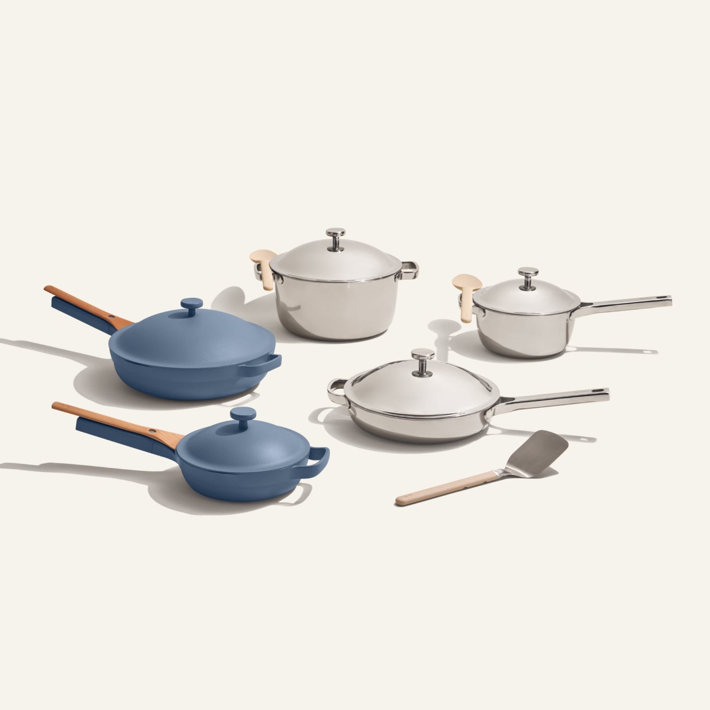 The Home Chef Set (15 piece) includes two blue ceramic pans, three silver pots with lids, a metal spatula, and more, all arranged on a light background.