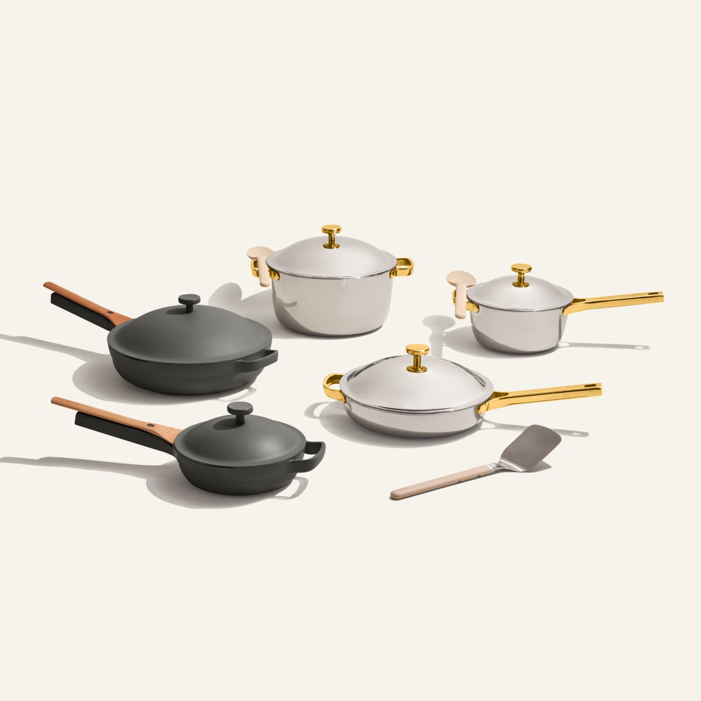 The Home Chef Set (15 piece) includes two black pans, three white ceramic pots with gold handles, and a metal spatula, all displayed on a light background.
