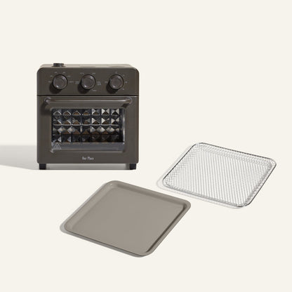 The Wonder Oven + Wonder Oven Essentials Kit includes a countertop oven with three control knobs, shown with a metal baking tray and mesh tray, displayed on a plain background.