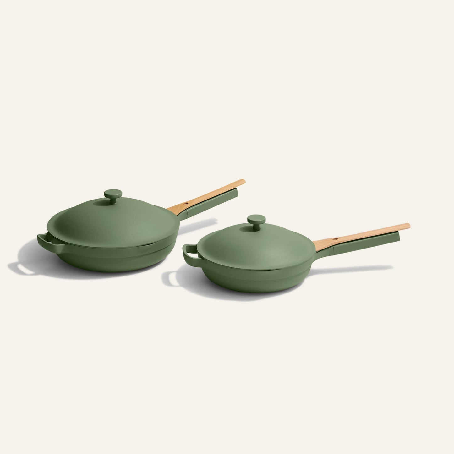 The Always Pan Duo features two green nonstick frying pans—with wooden handles and matching lids—inspired by the original Always Pan, side by side on a light background, making them perfect versatile cookware for any kitchen.