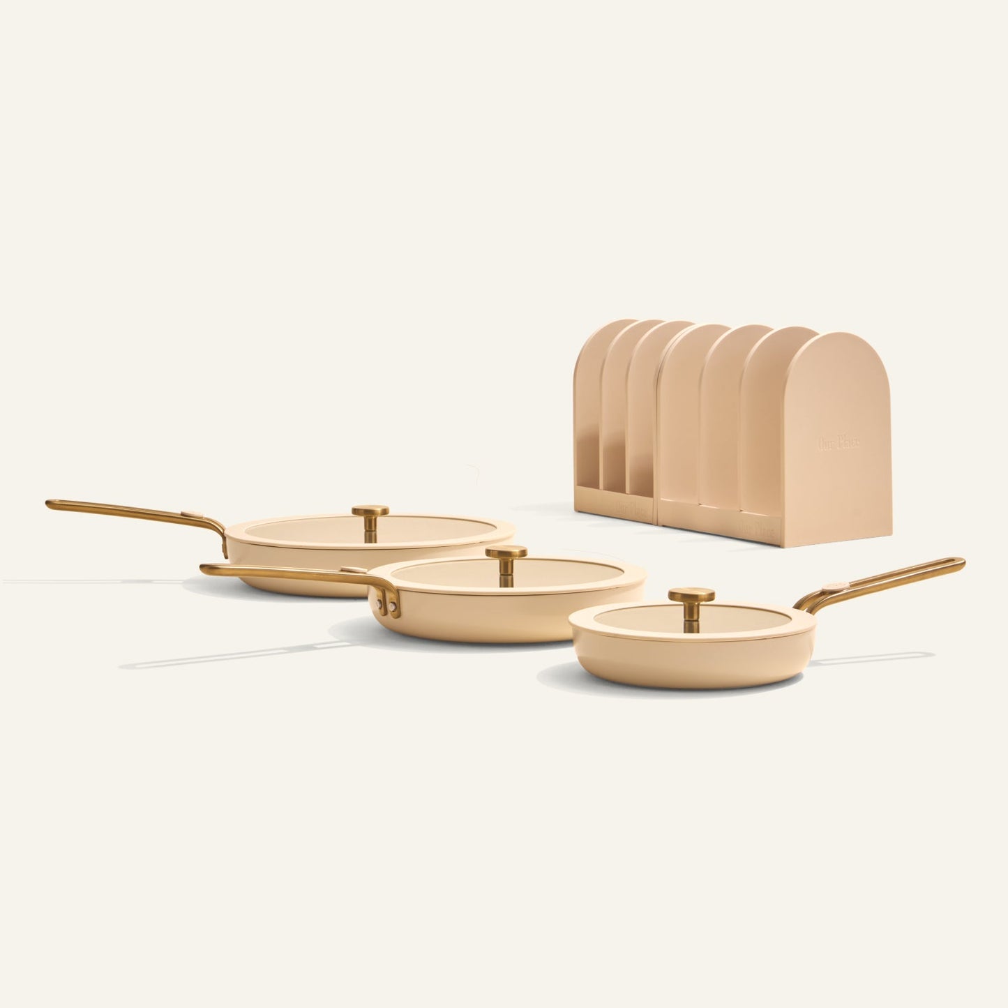 Set of three beige frying pans with gold handles on a white background