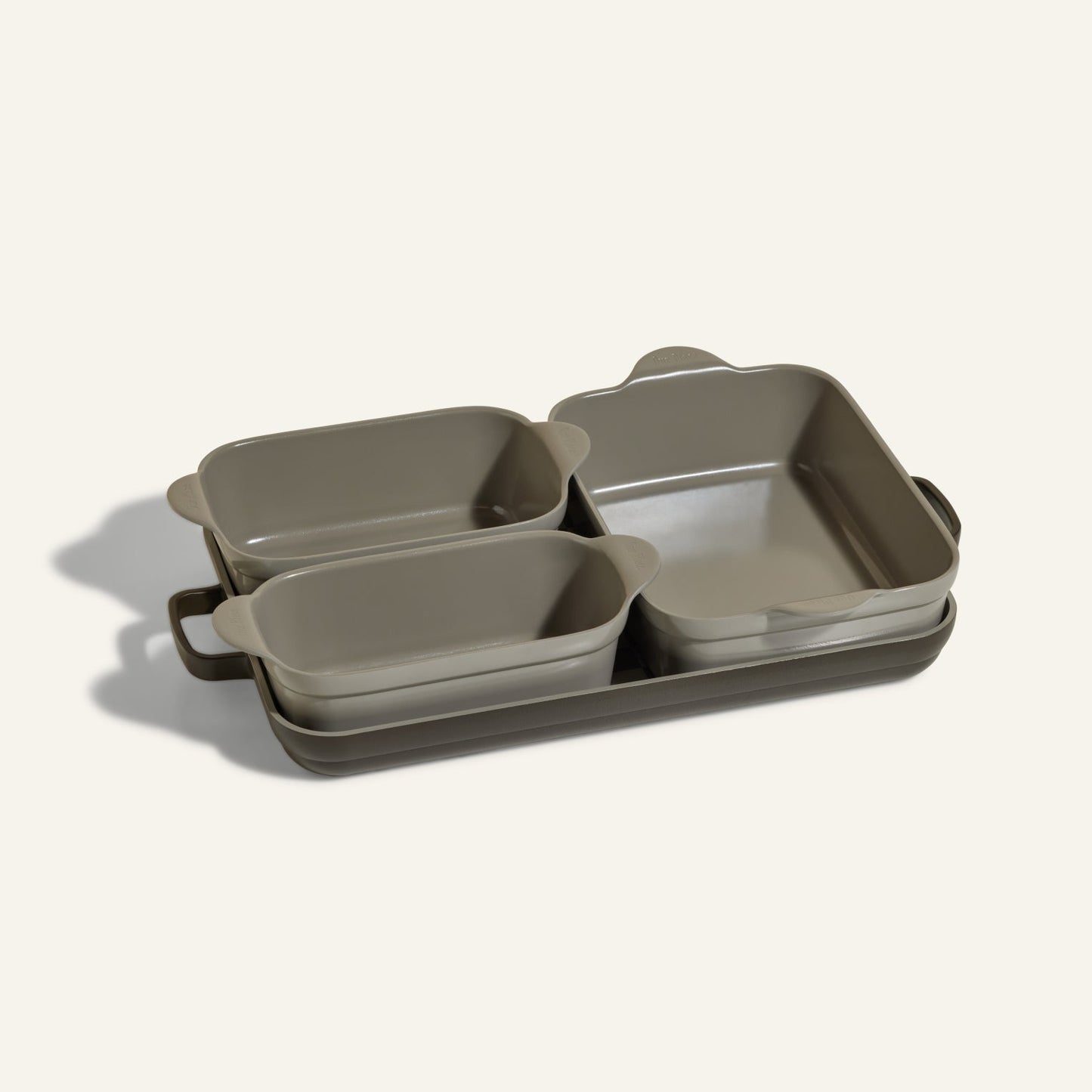 The Bakeware Set includes five stylish gray ceramic baking dishes—rectangular and square with handles—stacked on a matching tray, making it an essential addition to your oven cookware collection.