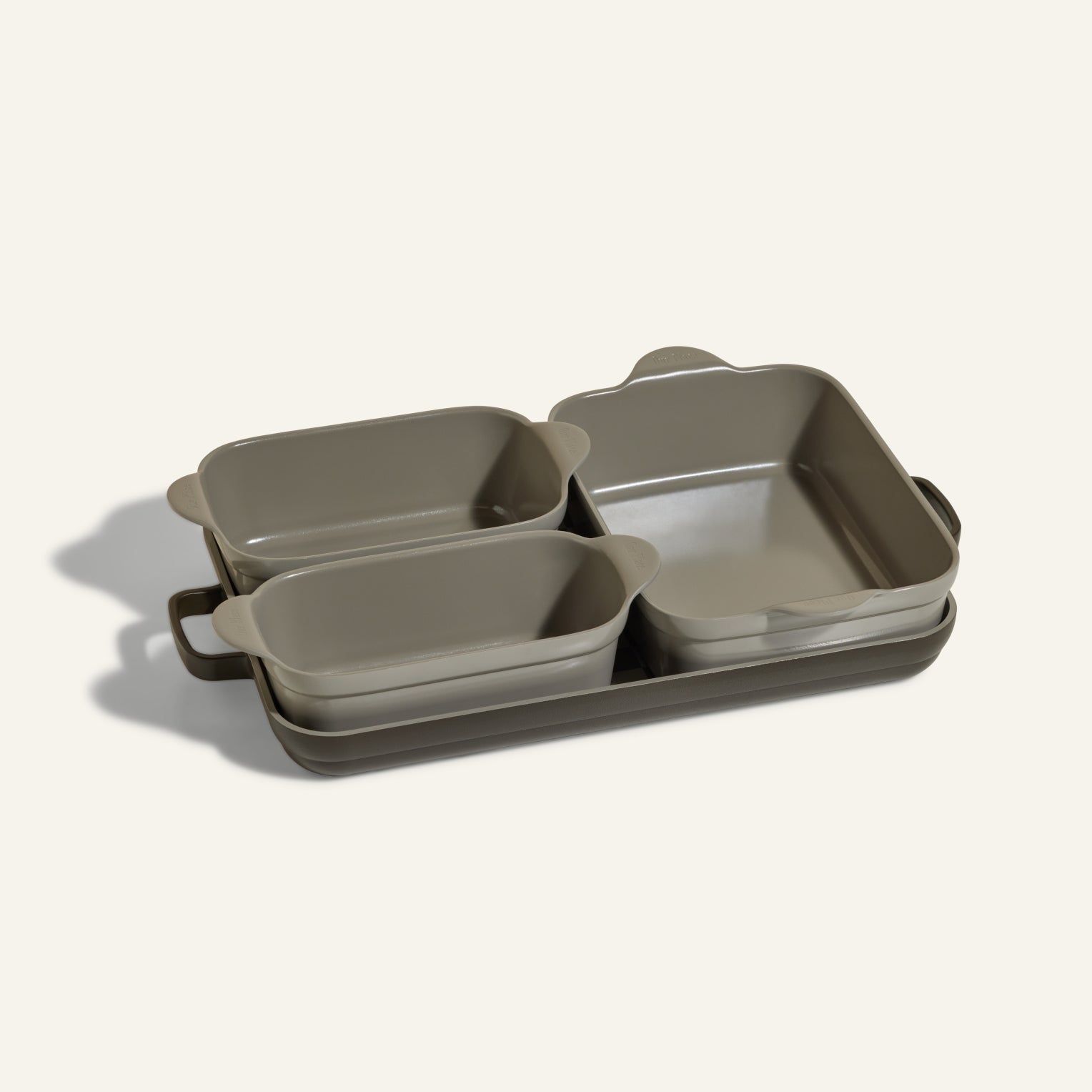 The Bakeware Set includes five stylish gray ceramic baking dishes—rectangular and square with handles—stacked on a matching tray, making it an essential addition to your oven cookware collection.