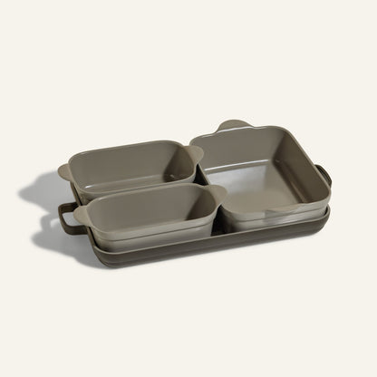 The Bakeware Set includes five stylish gray ceramic baking dishes—rectangular and square with handles—stacked on a matching tray, making it an essential addition to your oven cookware collection.