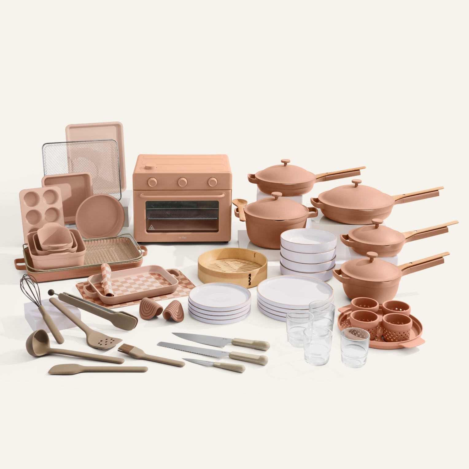 Collection of pink kitchenware including pots, pans, utensils, and cookware on a white background